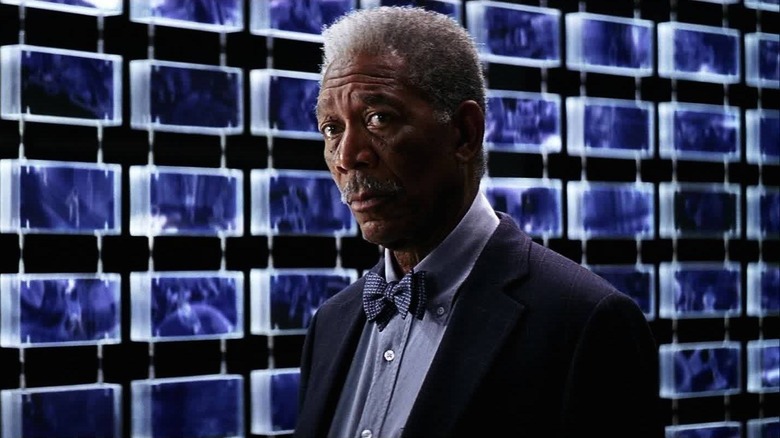 Lucius Fox looks at surveillance screens