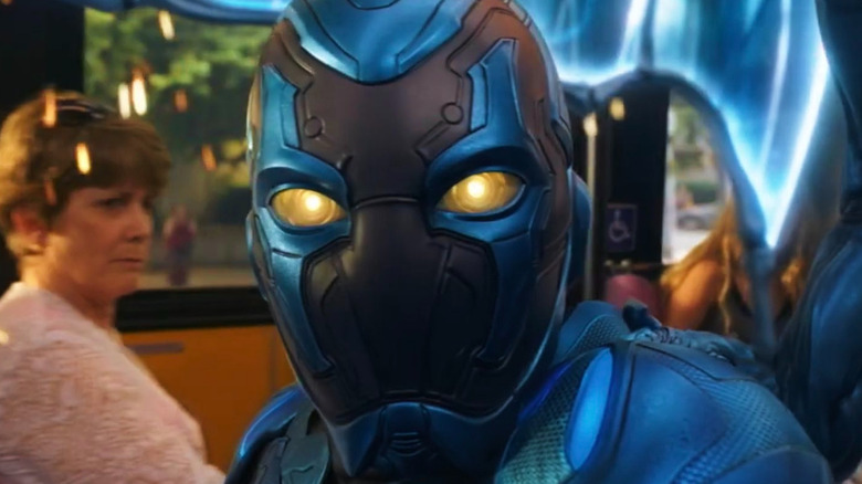 Blue Beetle looking at the bus passengers