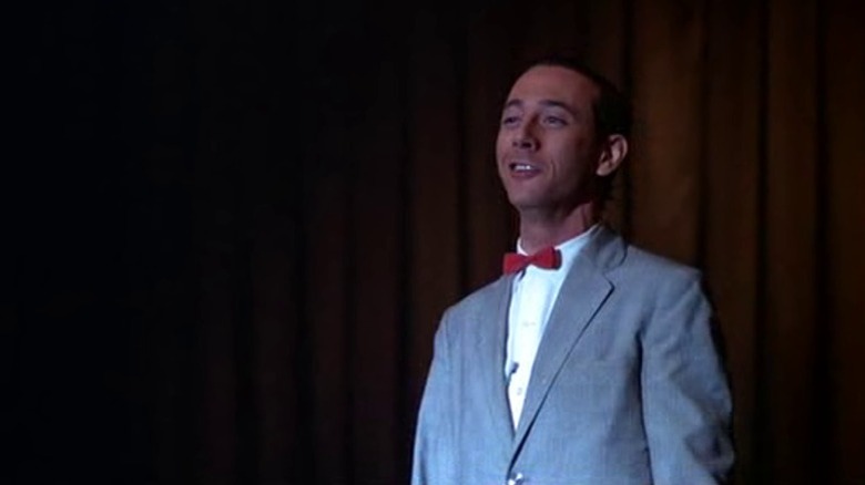 Pee-wee Herman smiling from atop a stage