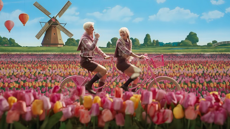 Barbie and Ken cycling in a colorful field