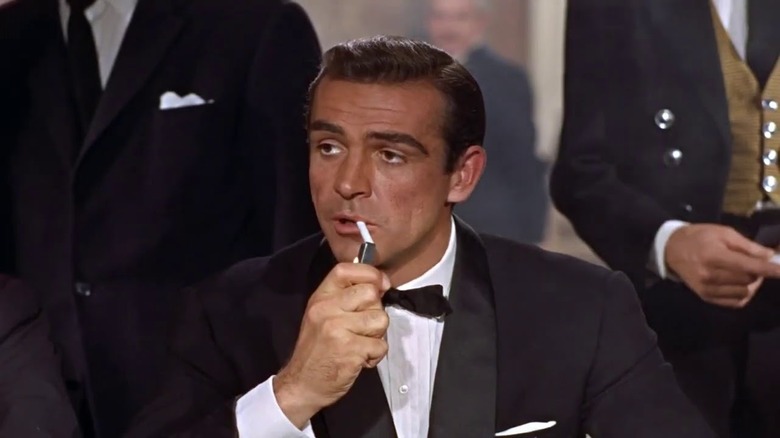 Bond lights a cigarette