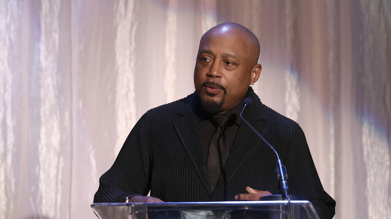 Daymond John speaking on stage at an event