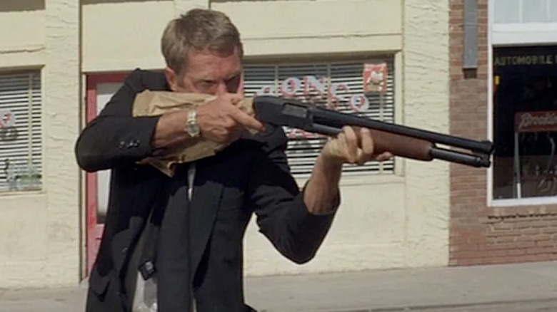 McQueen aims a shotgun