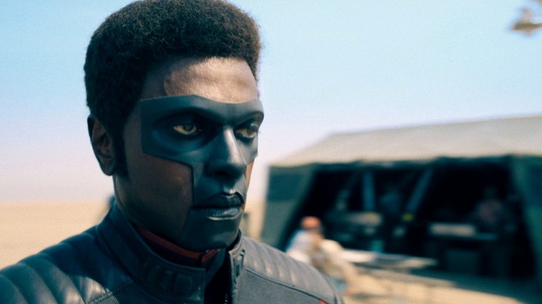 Mister Terrific standing in the desert with a tent in the background in Superman (2025)