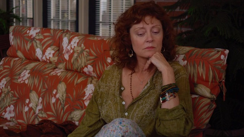 Susan Sarandon sits on a couch resting chin on hand