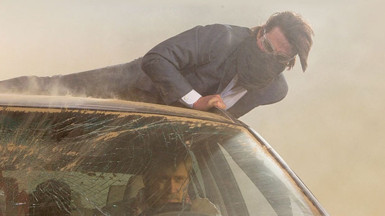 Ethan Hunt hangs on to a car in a sandstorm