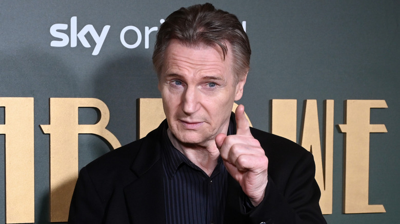 Liam Neeson pointing a finger at a premiere