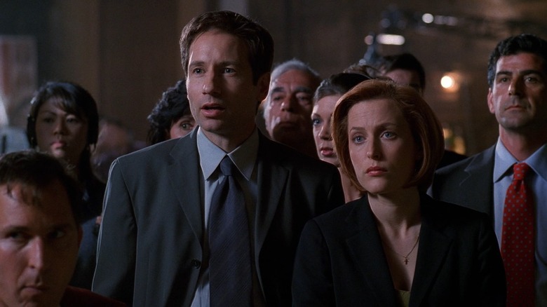 Scully and Mulder surrounded by people in suits