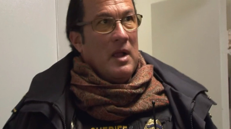 Steven Seagal wearing a scarf in a room