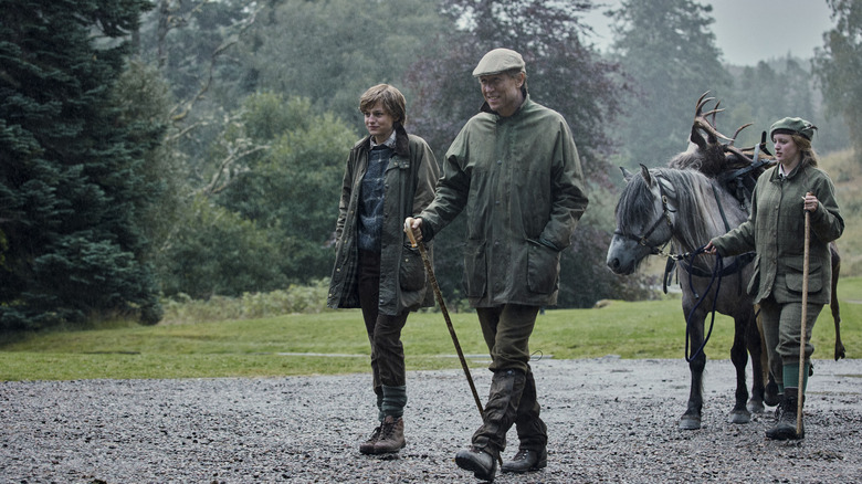 Emma Corrin, Tobias Menzies walking with horse