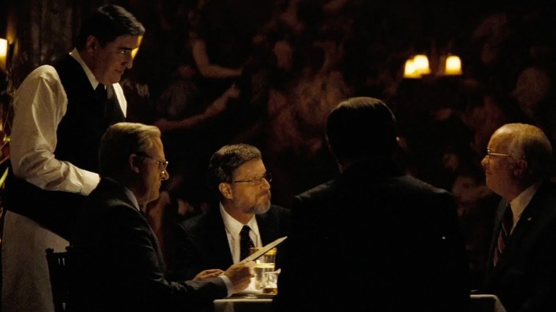 Christian Bale as Dick Cheney sitting with colleagues in fancy restaurant