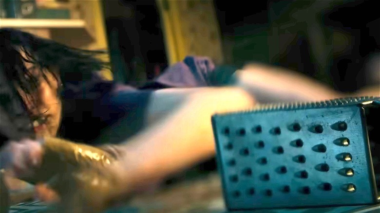 Beth on the floor reaching for a grater