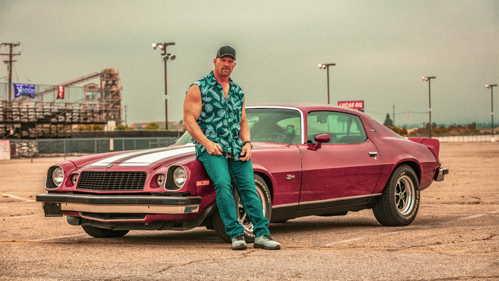 Steve Austin standing in front of a car