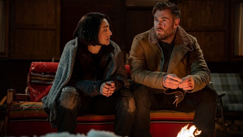 Ketevan and Tyler sit on a couch in front of a fire