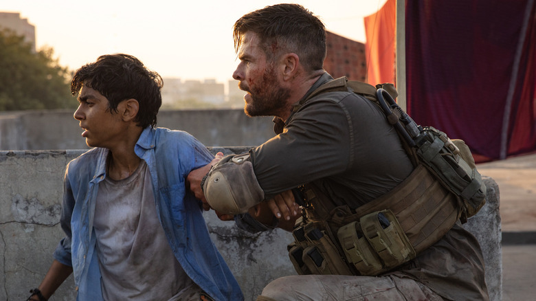 Chris Hemsworth, Rudhraksh Jaiswal crouching in Extraction