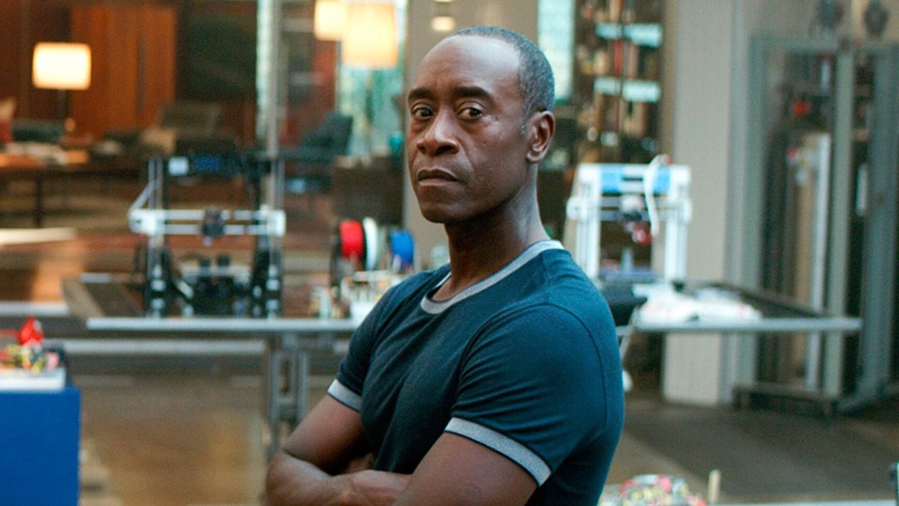 Don Cheadle stands in a lab with arms crossed