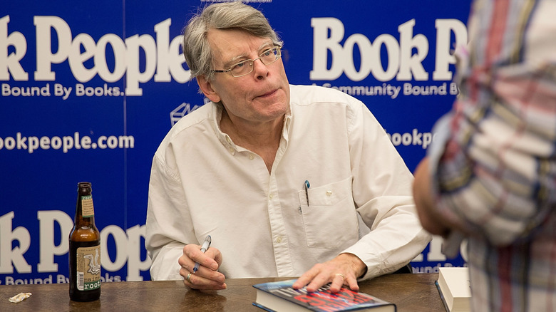 Stephen King smiling and signing books