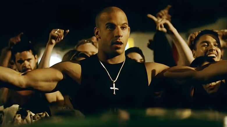 Dominic Toretto standing in front of a crowd with his arms outstretched