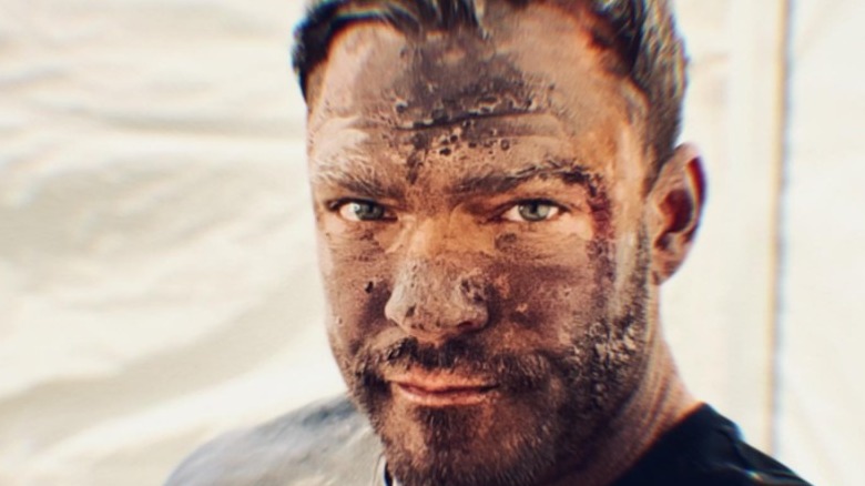 Alan Ritchson smiling with dirt on face