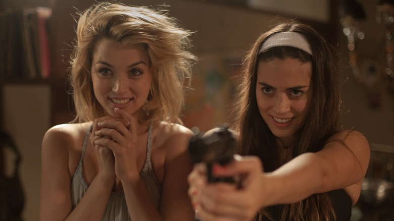 Ana De Armas and Lorenza Izzo smiling with a gun