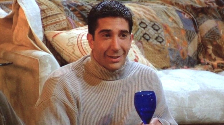 Ross Geller smiling to the right holding blue glass