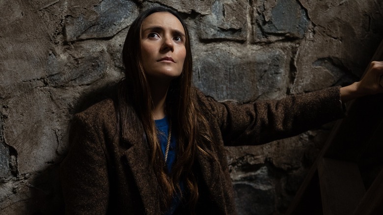 Tabitha stands against a stone wall