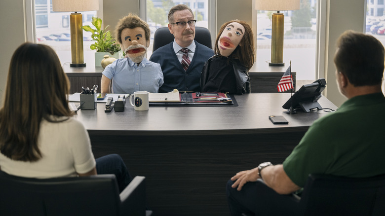 Dr. Pfeffer holds up two puppets at his desk