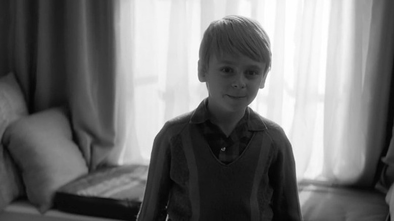 Little blond haired boy in sweater vest, black and white