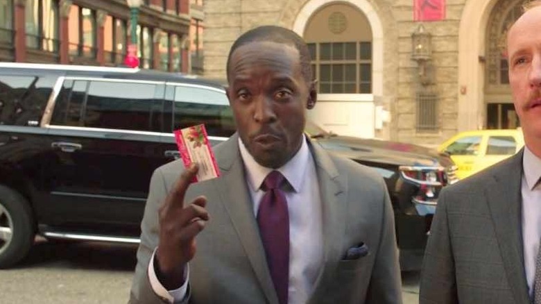 Michael K Williams holds up a business card