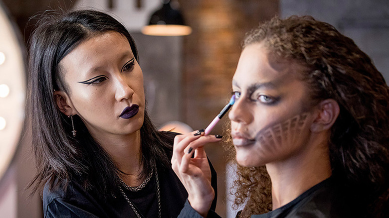 Season 2 contestant doing makeup on a model in Glow Up