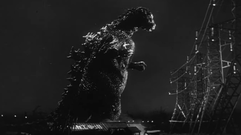 Godzilla standing before electric fence