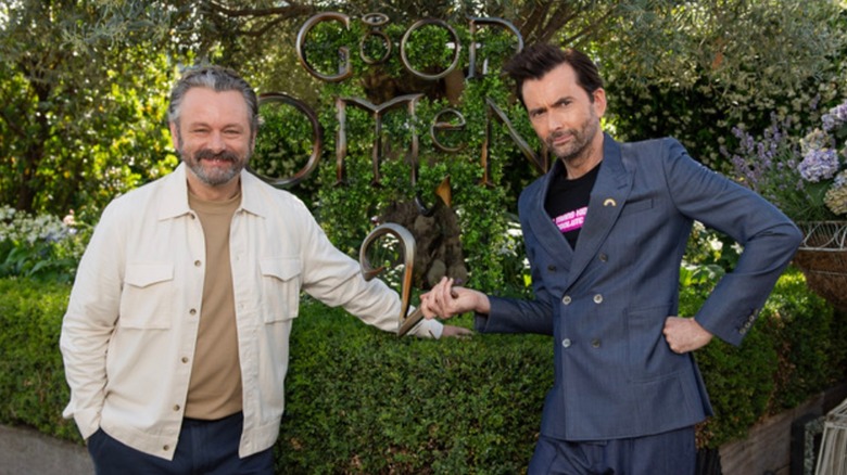 Michael Sheen smiling, David Tennant serious hand on hip