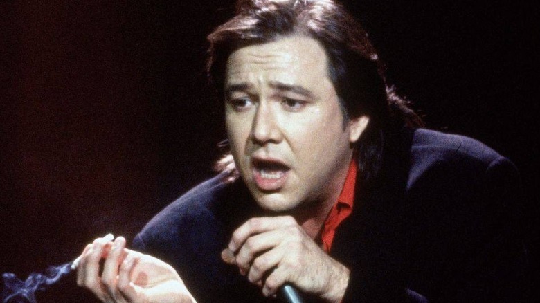 Bill Hicks holds a cigarette and mic