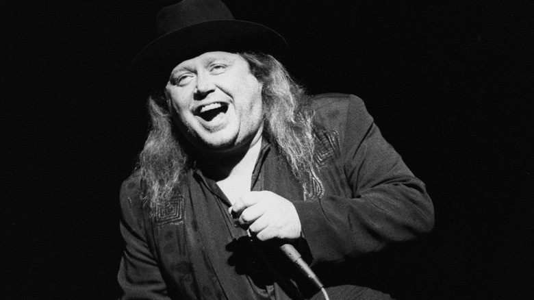 Sam Kinison holds a mic