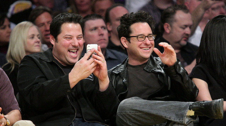 Greg Grunberg and J.J. Abrams sitting and laughing together at a Lakers game