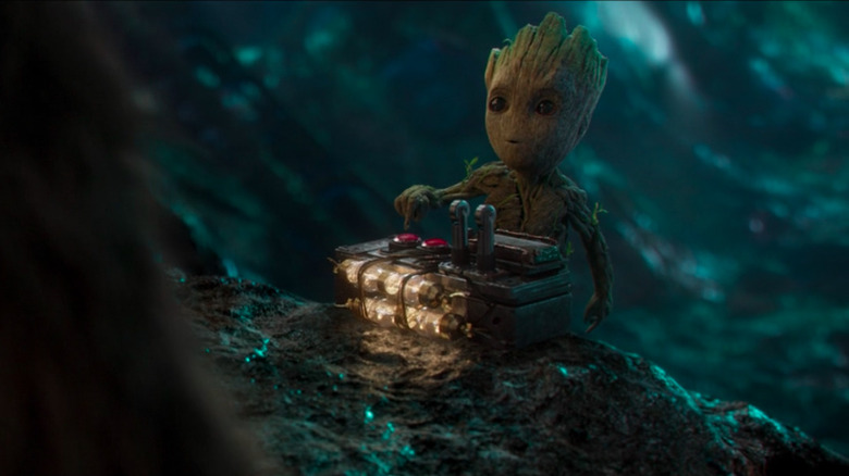 Baby Groot points to a red button on an explosive