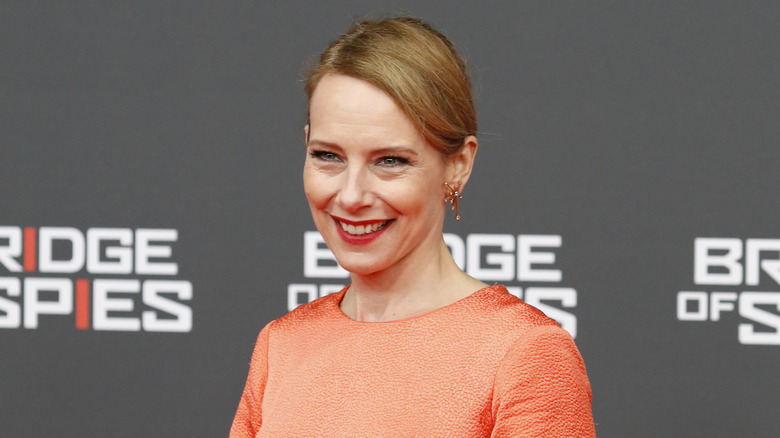 Amy Ryan, in a coral dress, gives a smile