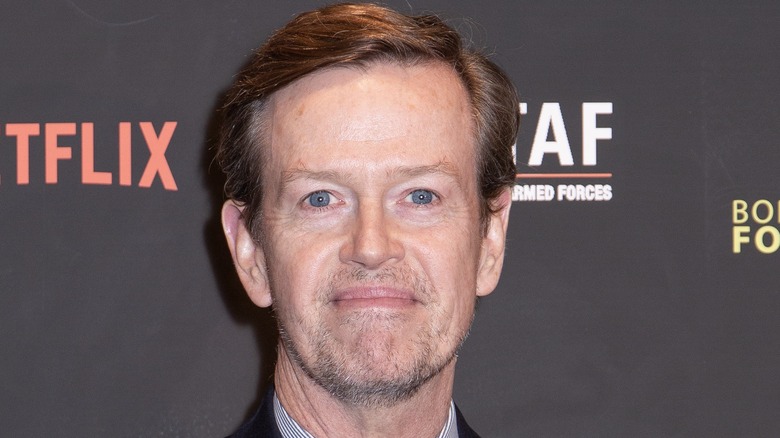 A bearded Dylan Baker offers a smile