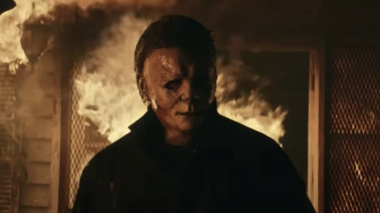 Michael Myers stands in front of a burning house