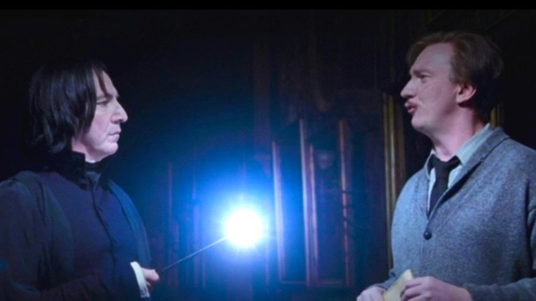 Severus Snape holding up a lit wand to Remus Lupin