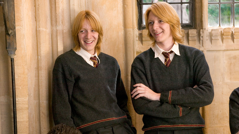 Fred and George leaning on wall laughing