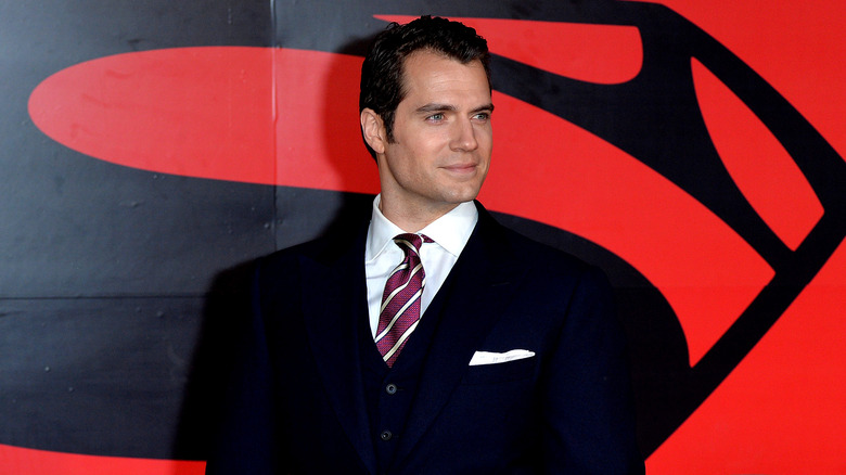 Henry Cavill standing before the Superman logo