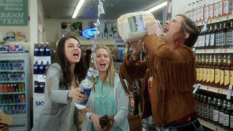 Mila Kunis, Kristen Bell, and Kathryn Hahn pouring drinks in a store