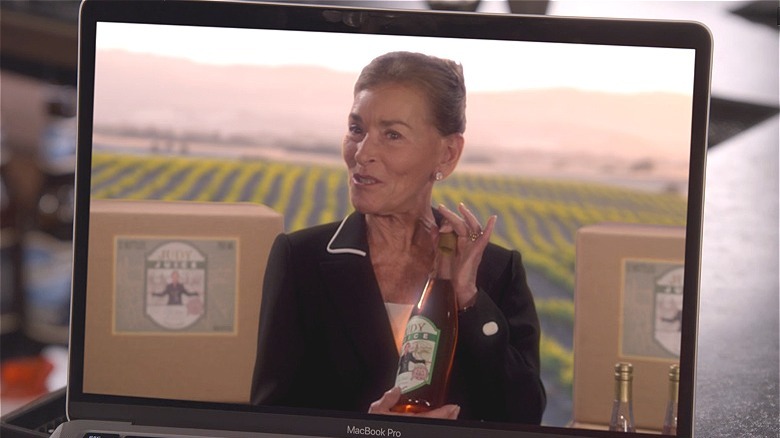 Judge Judy showing off the Judy Juice wine in a commercial on a laptop