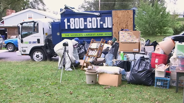 1-800-GOT-JUNK? worker emptying hoard onto grass