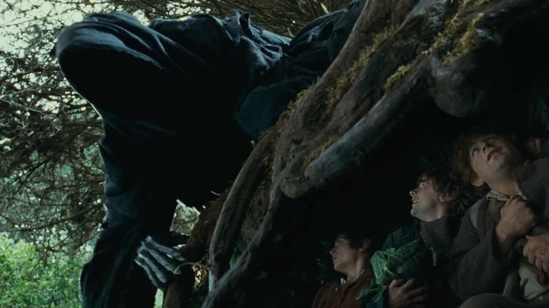 A Black Rider over Hobbits hiding in a tree stump