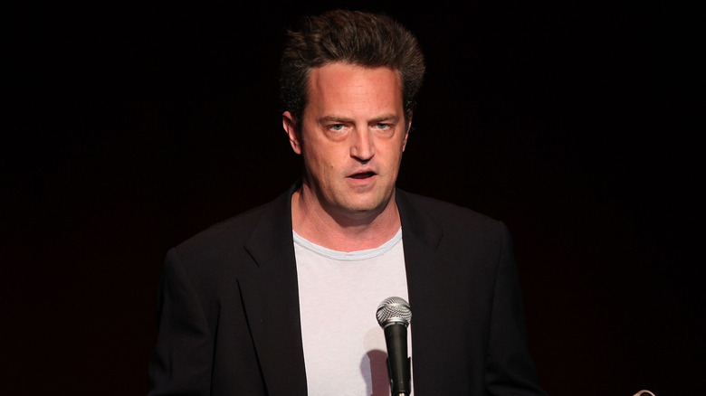 Matthew Perry speaking into a microphone