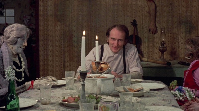 Ezra Cobb dines at a table with two women's corpses in "Deranged" (1974)