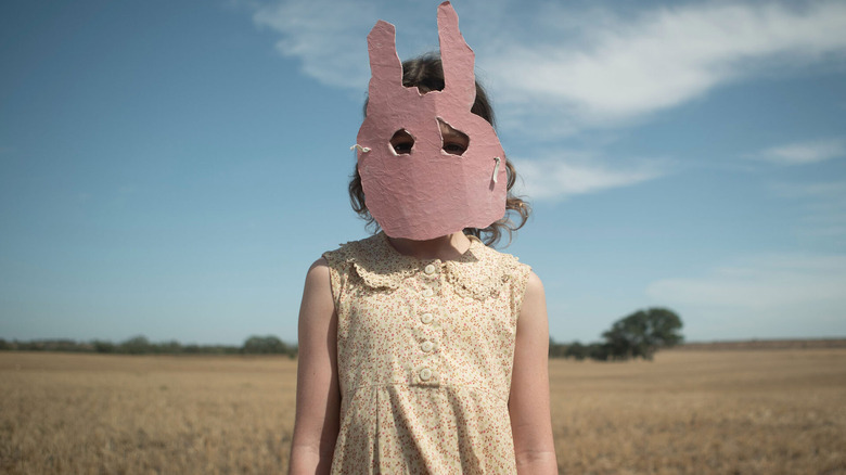 Mia wears her rabbit mask against a blue sky in "Run Rabbit Run" (2023)