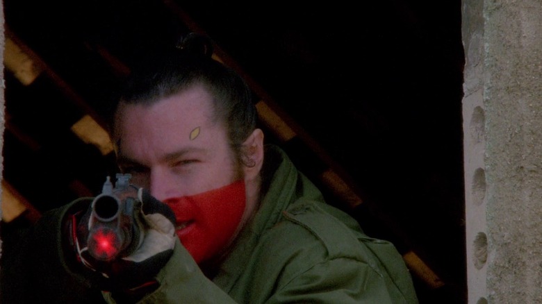 Paul White aims a gun in "White of the Eye" (1987)